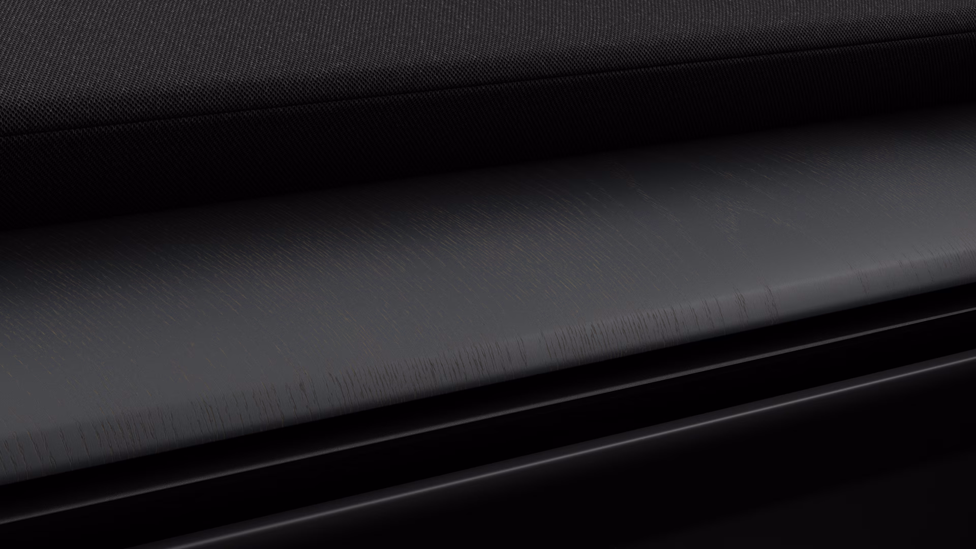 Крупный план материалов интерьера автомобиля Volvo, на котором видна текстурированная черная ткань и матовая деревянная отделка.