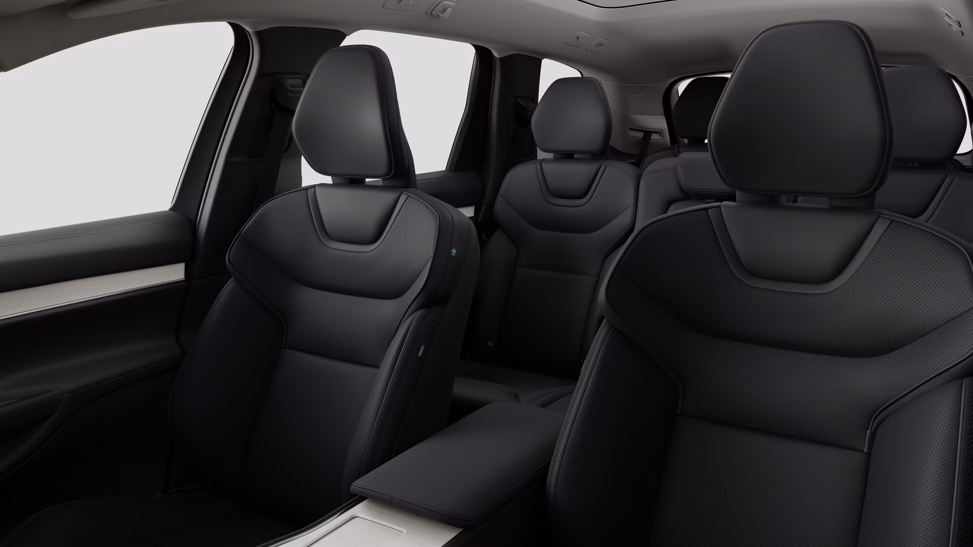 Салон автомобиля Volvo с задними пассажирскими сиденьями и центральной консолью на простом фоне студии.