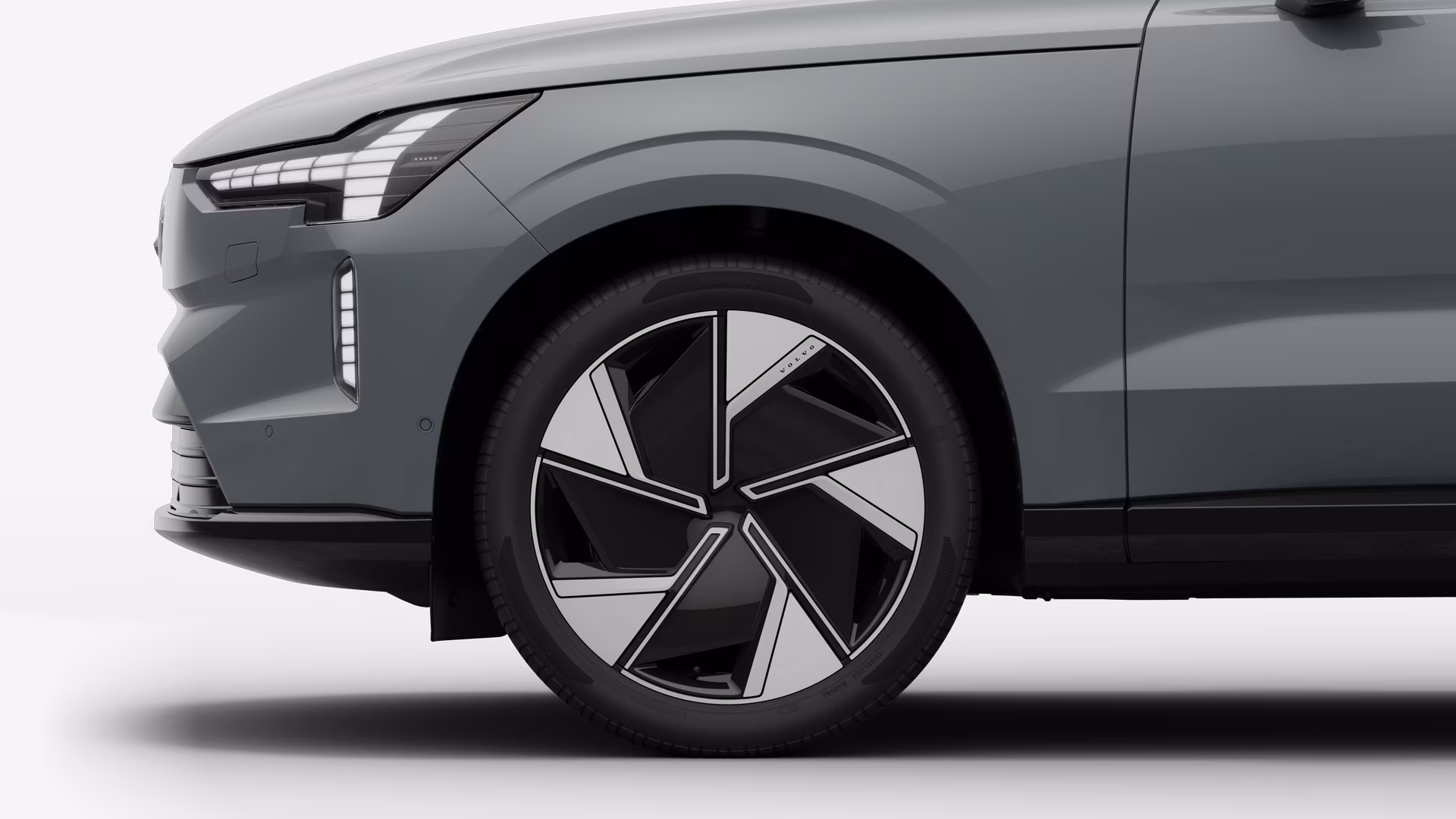 Вид сбоку на переднее колесо и крыло автомобиля Volvo на однотонном студийном фоне.
