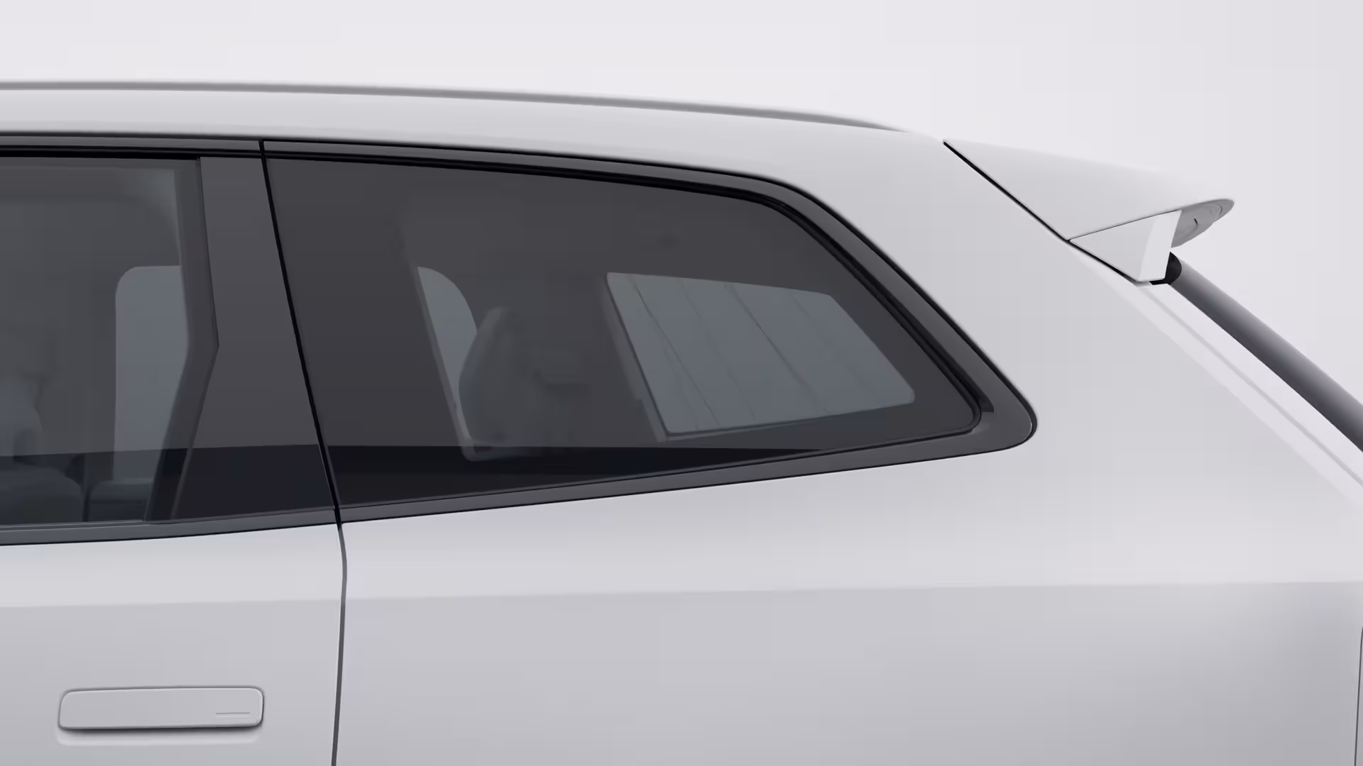 Крупный план заднего бокового окна и двери белого автомобиля Volvo, подчеркивающий дизайн окон и задний спойлер.