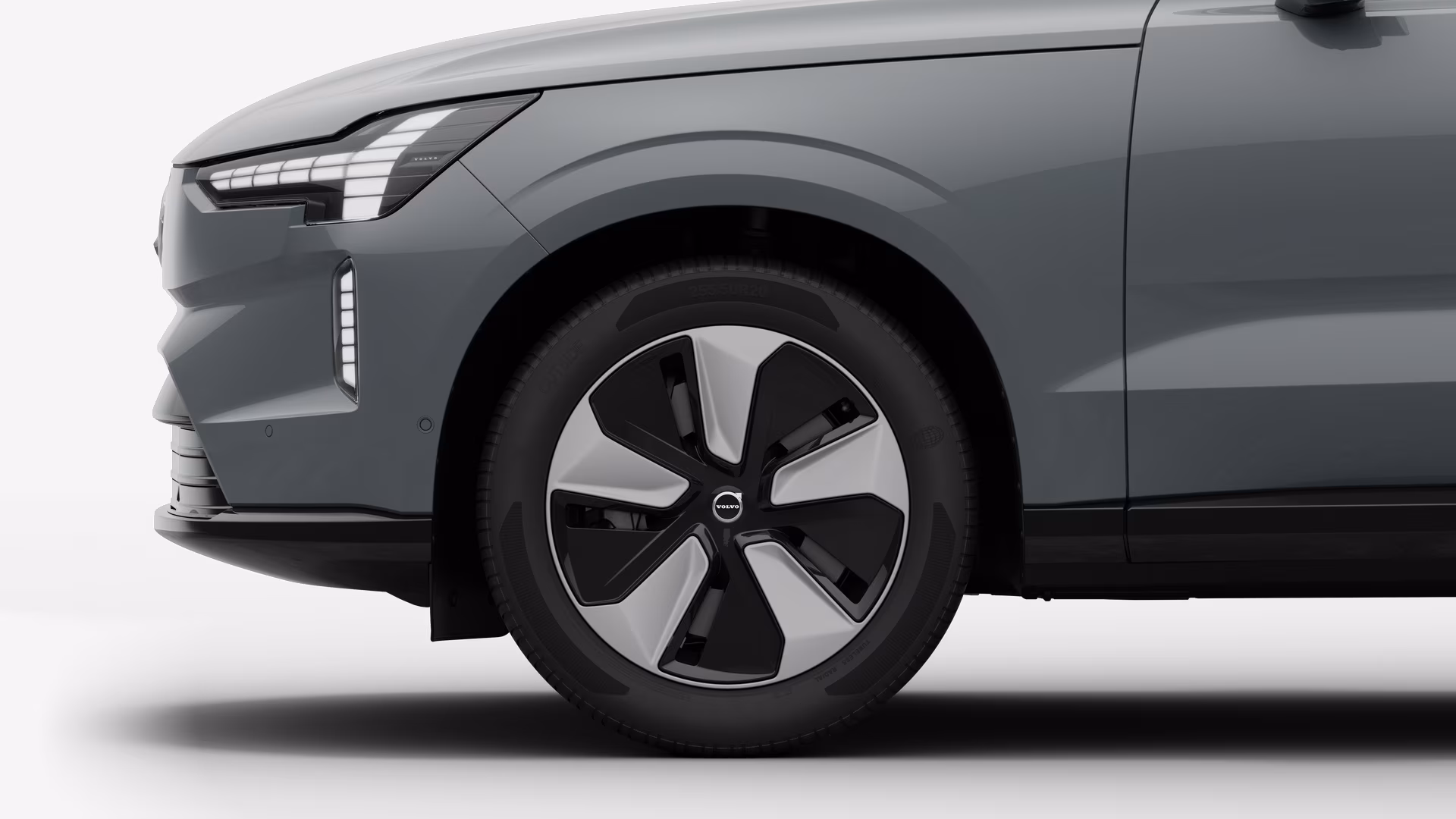 Вид сбоку на переднее колесо и крыло автомобиля Volvo на однотонном студийном фоне.