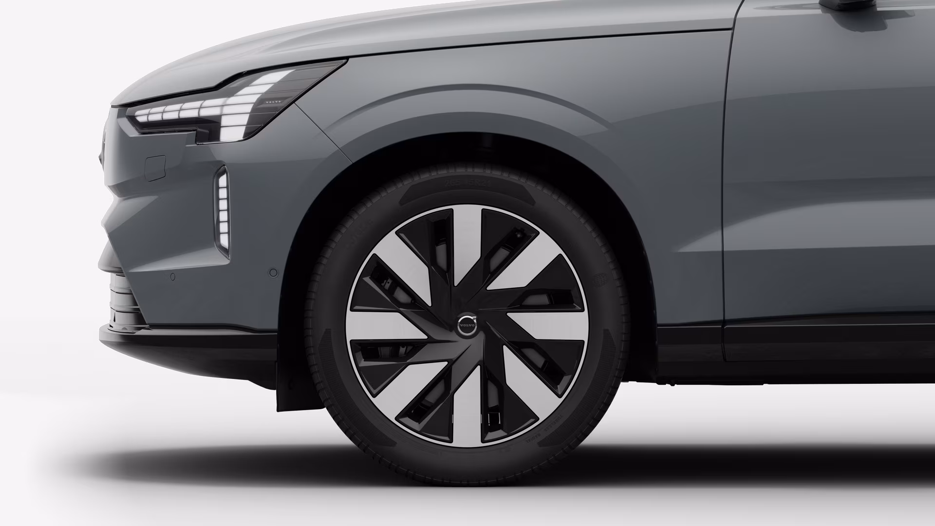 Вид сбоку на переднее колесо и крыло автомобиля Volvo на однотонном студийном фоне.