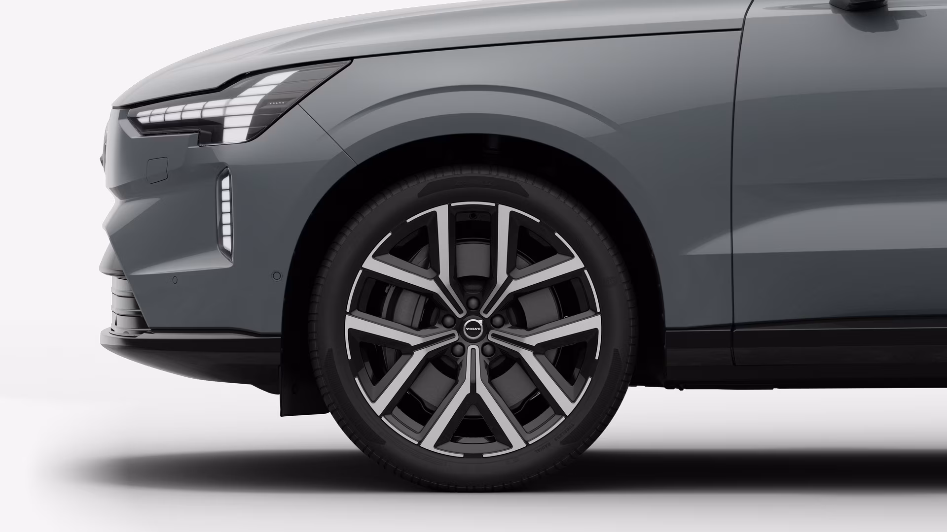 Вид сбоку на переднее колесо и крыло автомобиля Volvo на однотонном студийном фоне.