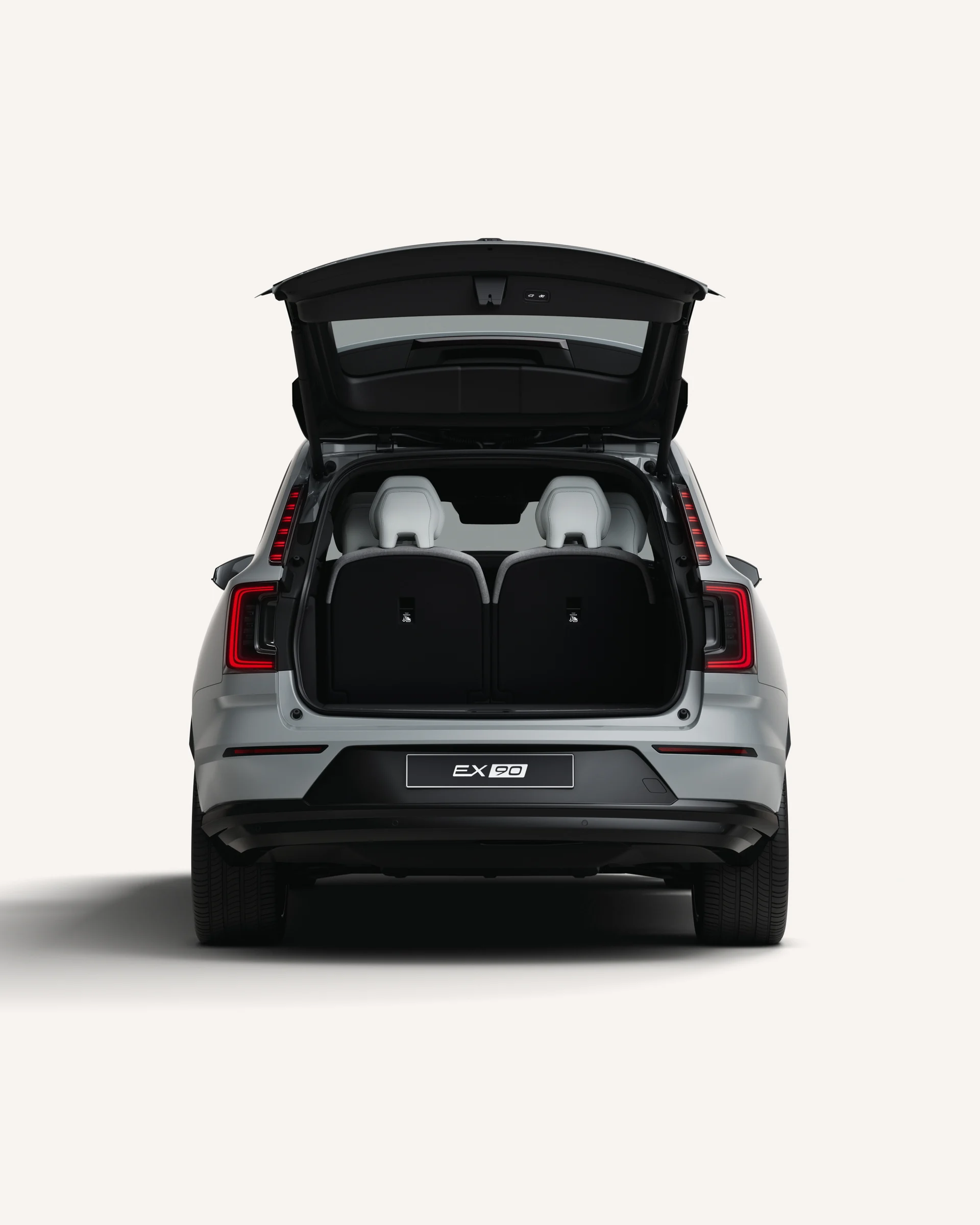 Вид сзади на Volvo EX90 с открытым багажником в белой студии. 