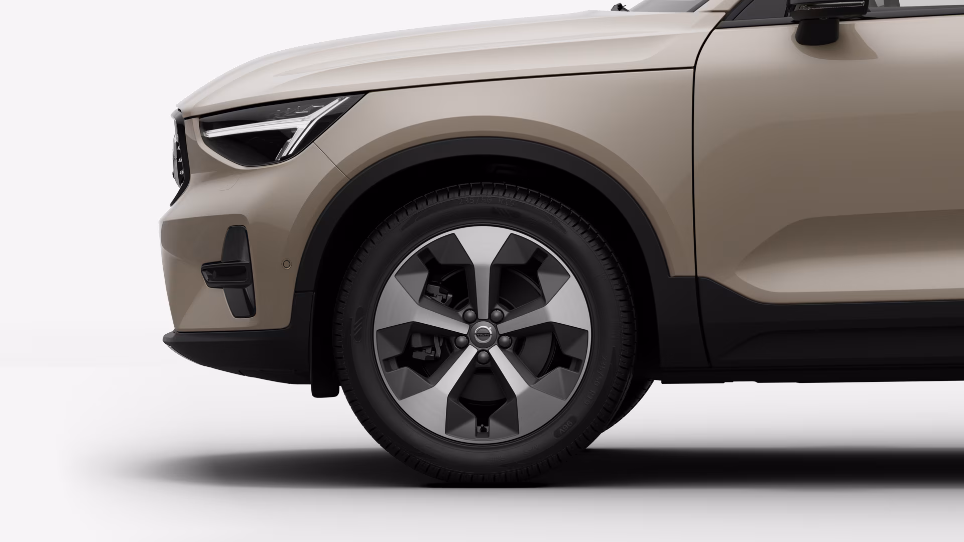 Вид сбоку на переднее колесо и крыло автомобиля Volvo на однотонном студийном фоне.