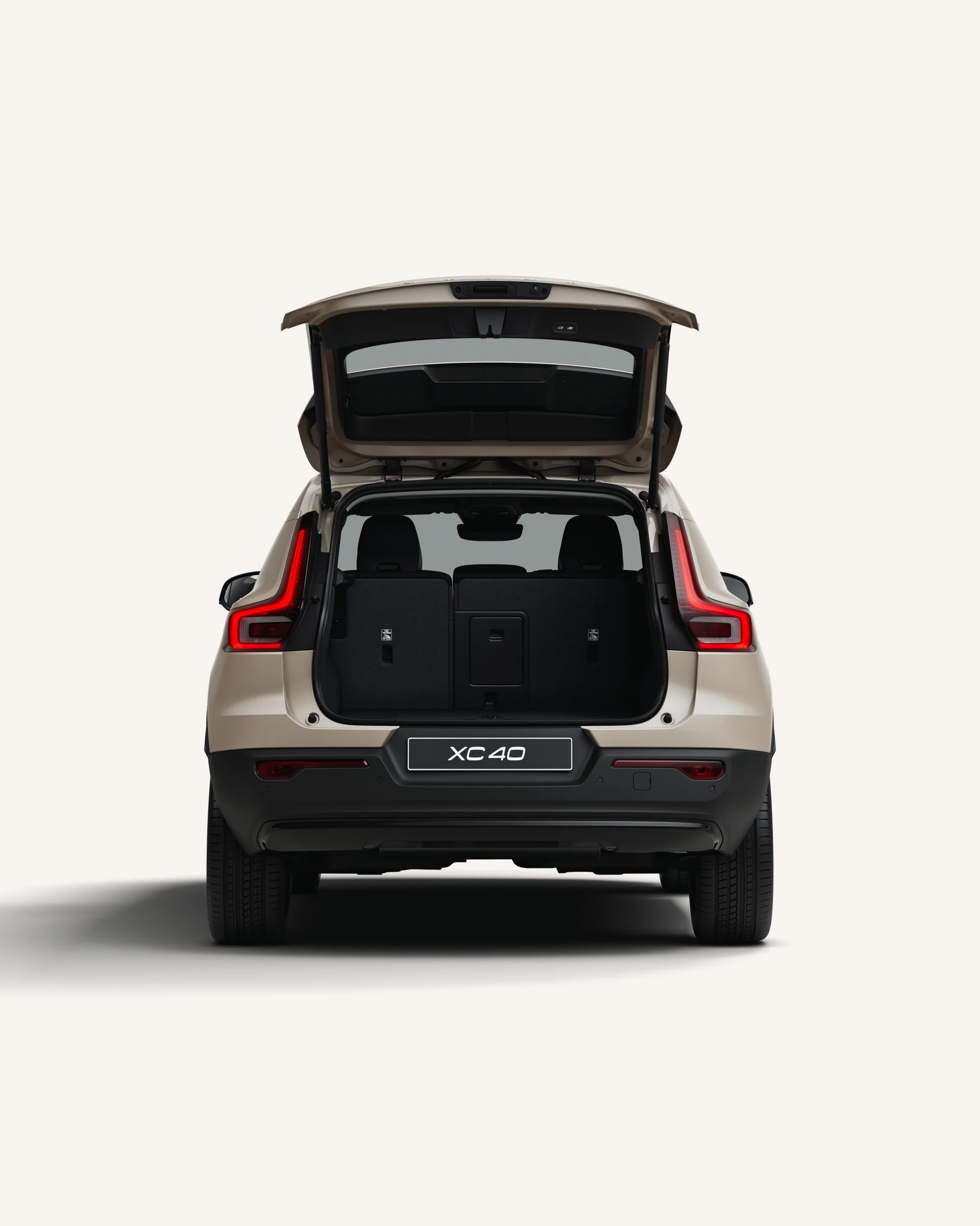Вид сзади на Volvo XC40 с открытым багажником в белой студии. 