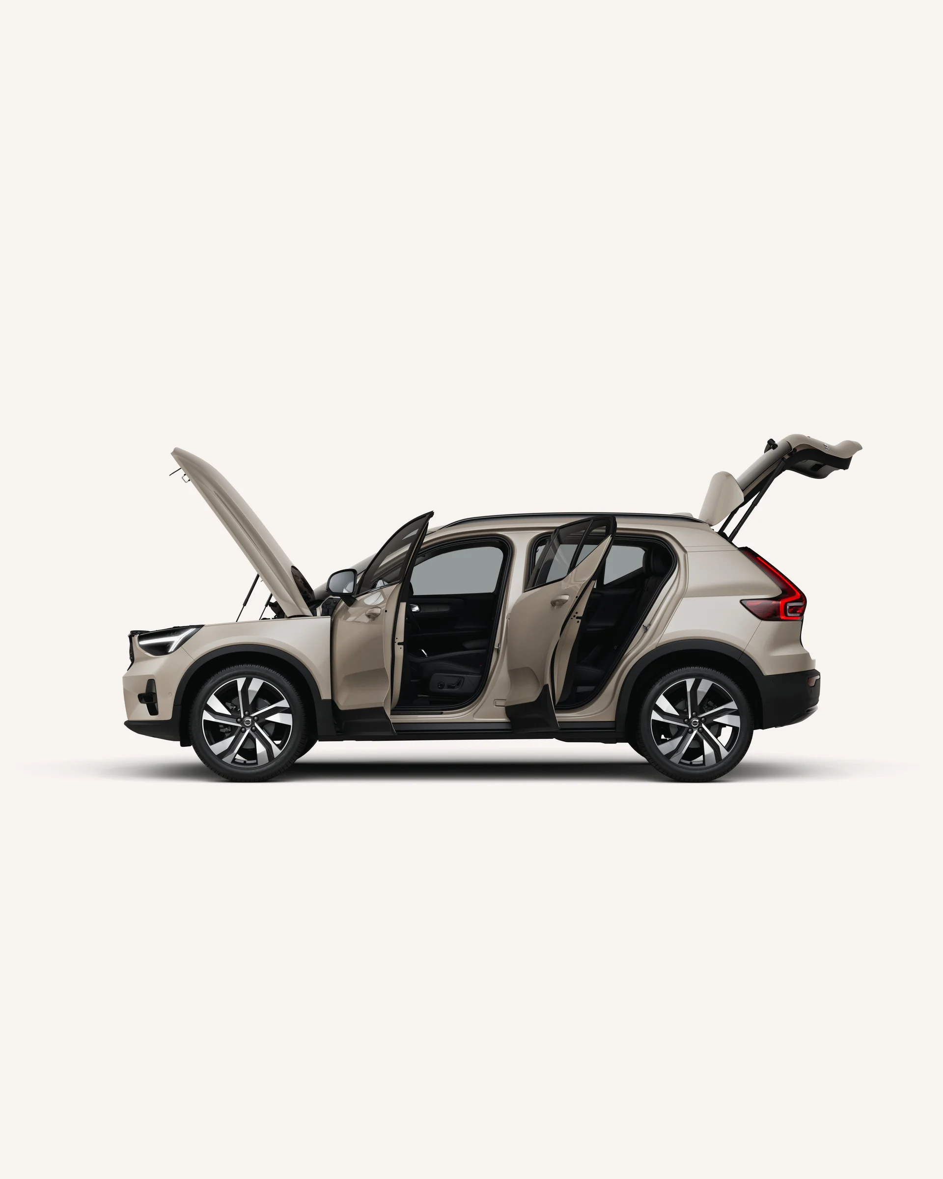 Вид сбоку на мягкий гибридный внедорожник Volvo XC40 с открытым капотом, дверями и багажником в белой студии.