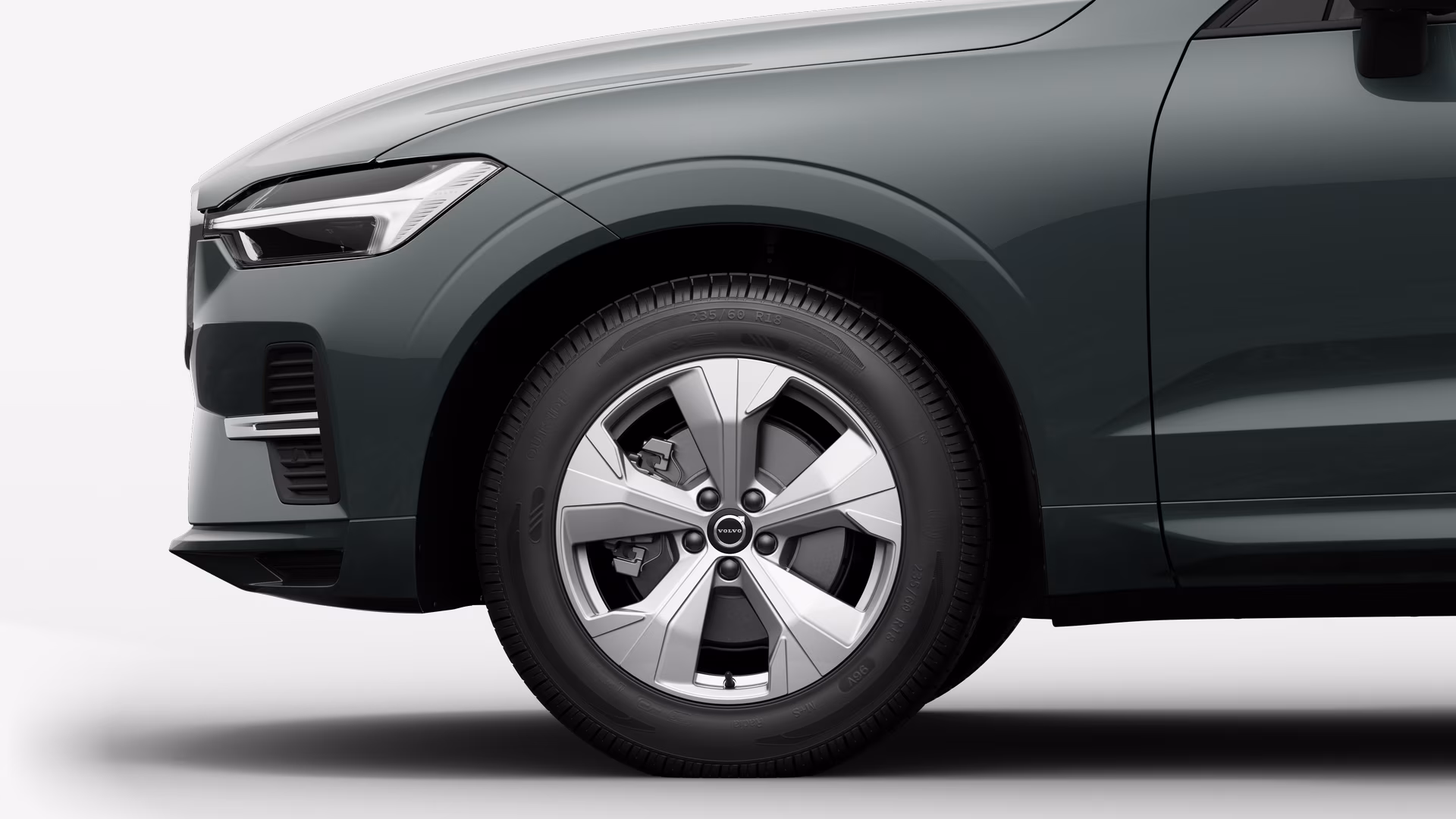 Вид сбоку на переднее колесо и крыло автомобиля Volvo на однотонном студийном фоне.