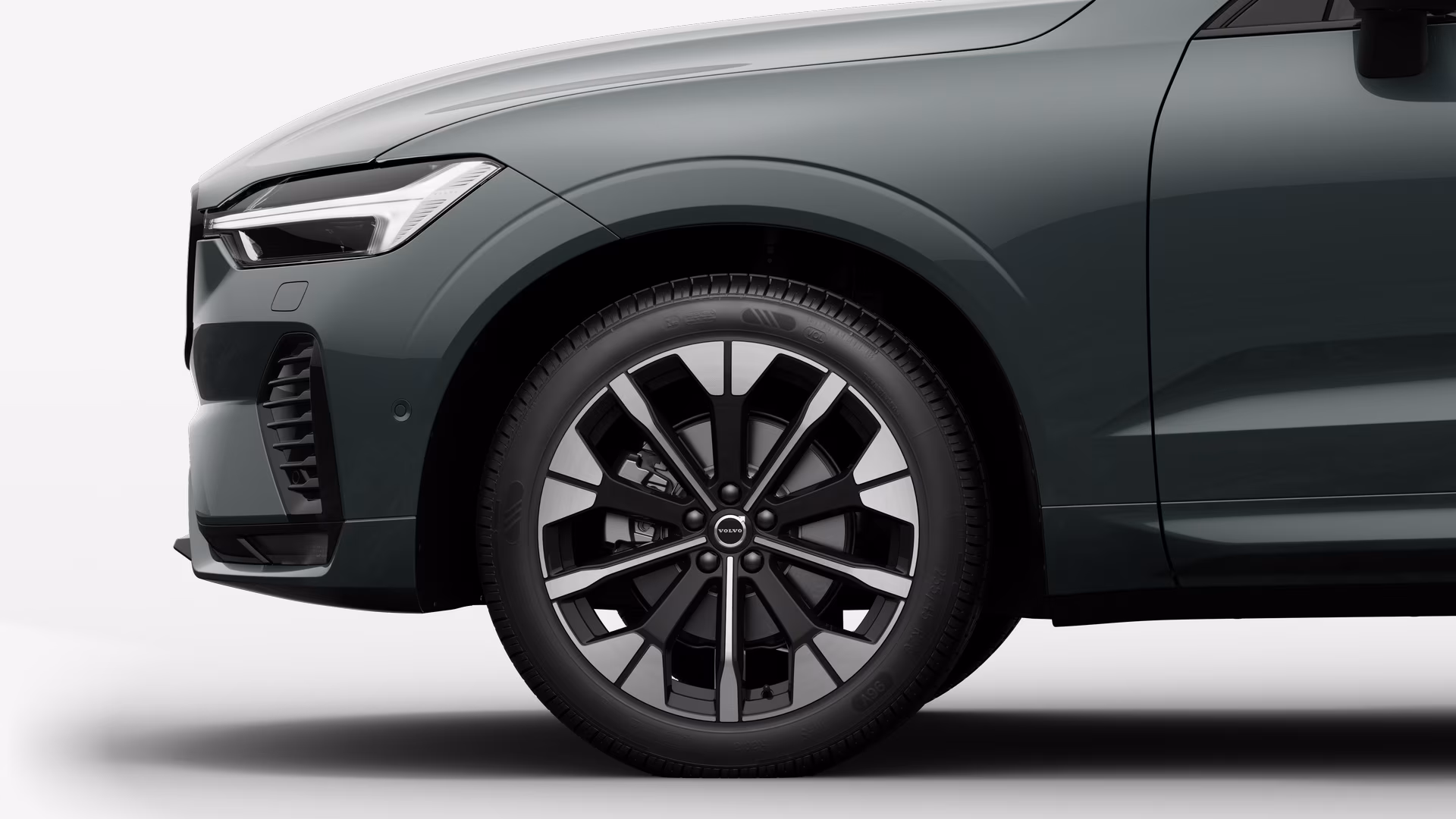 Вид сбоку на переднее колесо и крыло автомобиля Volvo на однотонном студийном фоне.