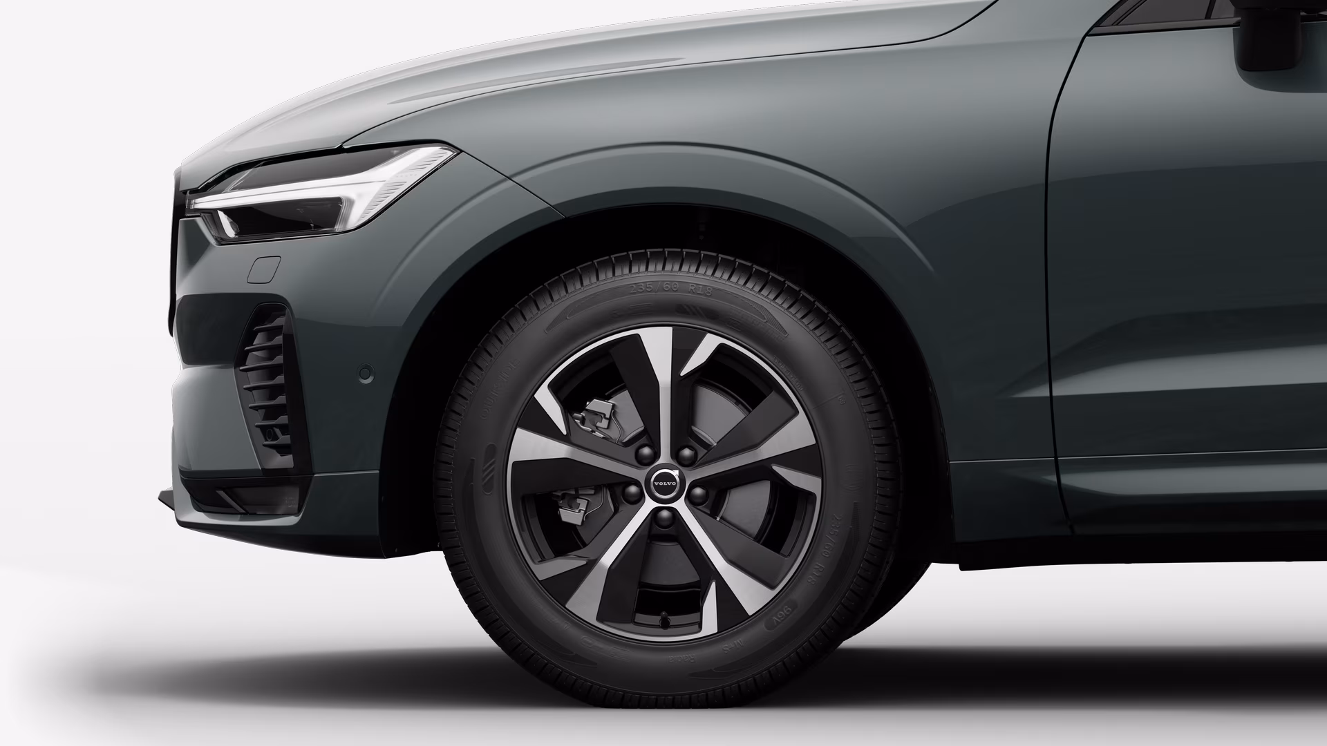 Вид сбоку на переднее колесо и крыло автомобиля Volvo на однотонном студийном фоне.
