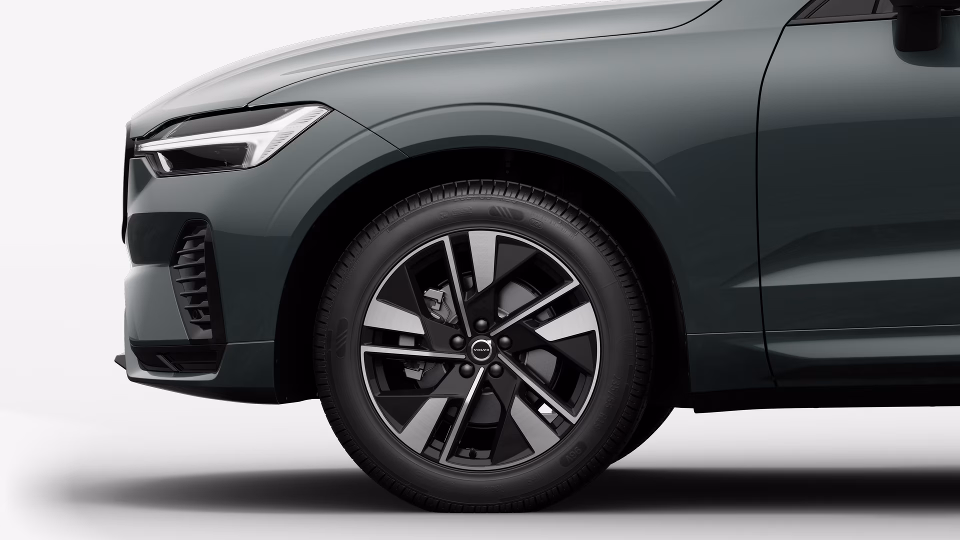 Вид сбоку на переднее колесо и крыло автомобиля Volvo на однотонном студийном фоне.