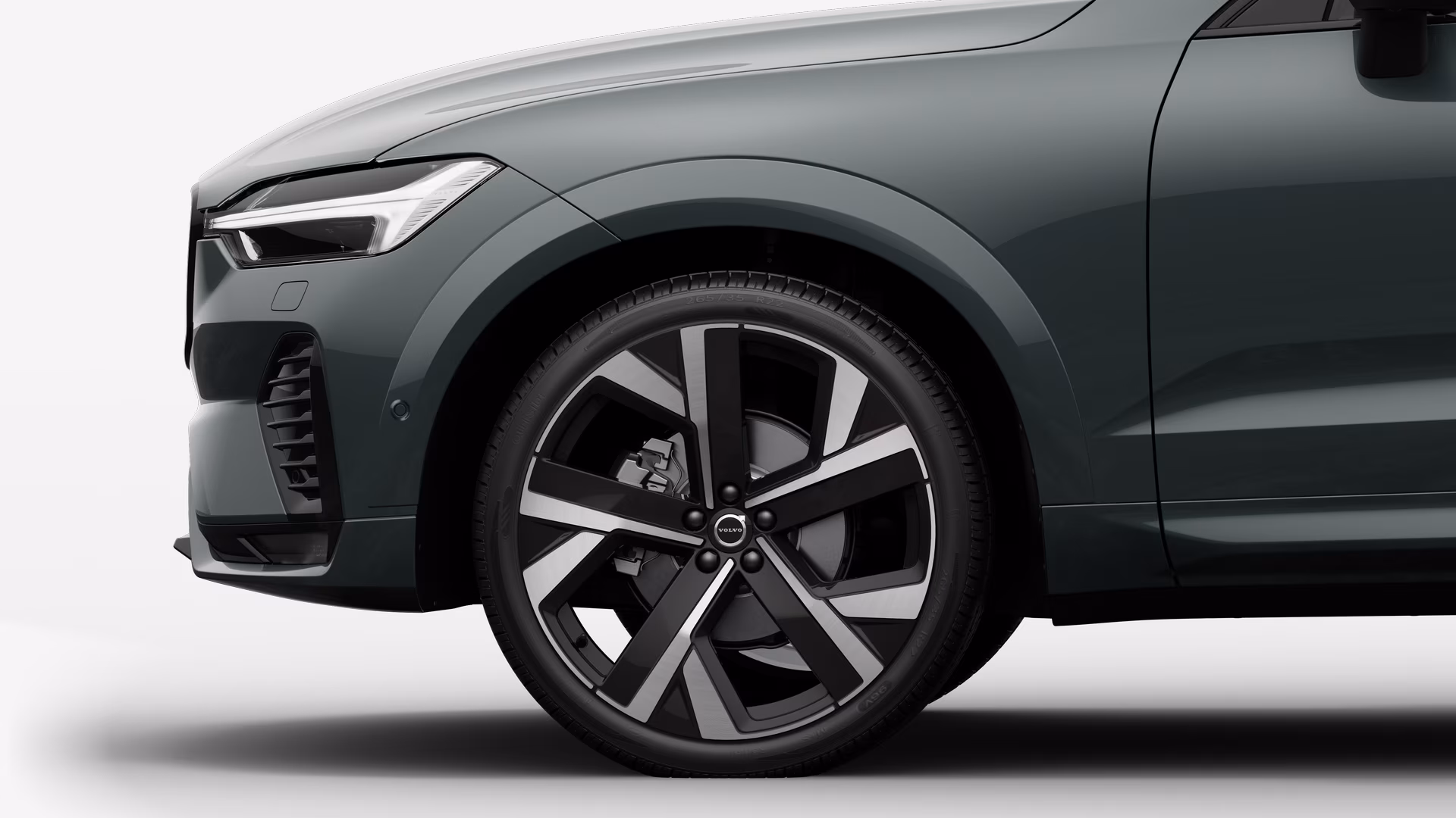 Вид сбоку на переднее колесо и крыло автомобиля Volvo на однотонном студийном фоне.