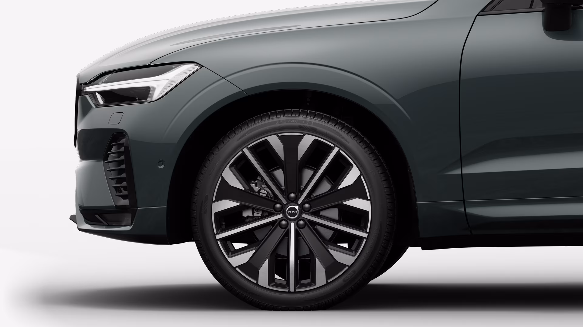 Вид сбоку на переднее колесо и крыло автомобиля Volvo на однотонном студийном фоне.