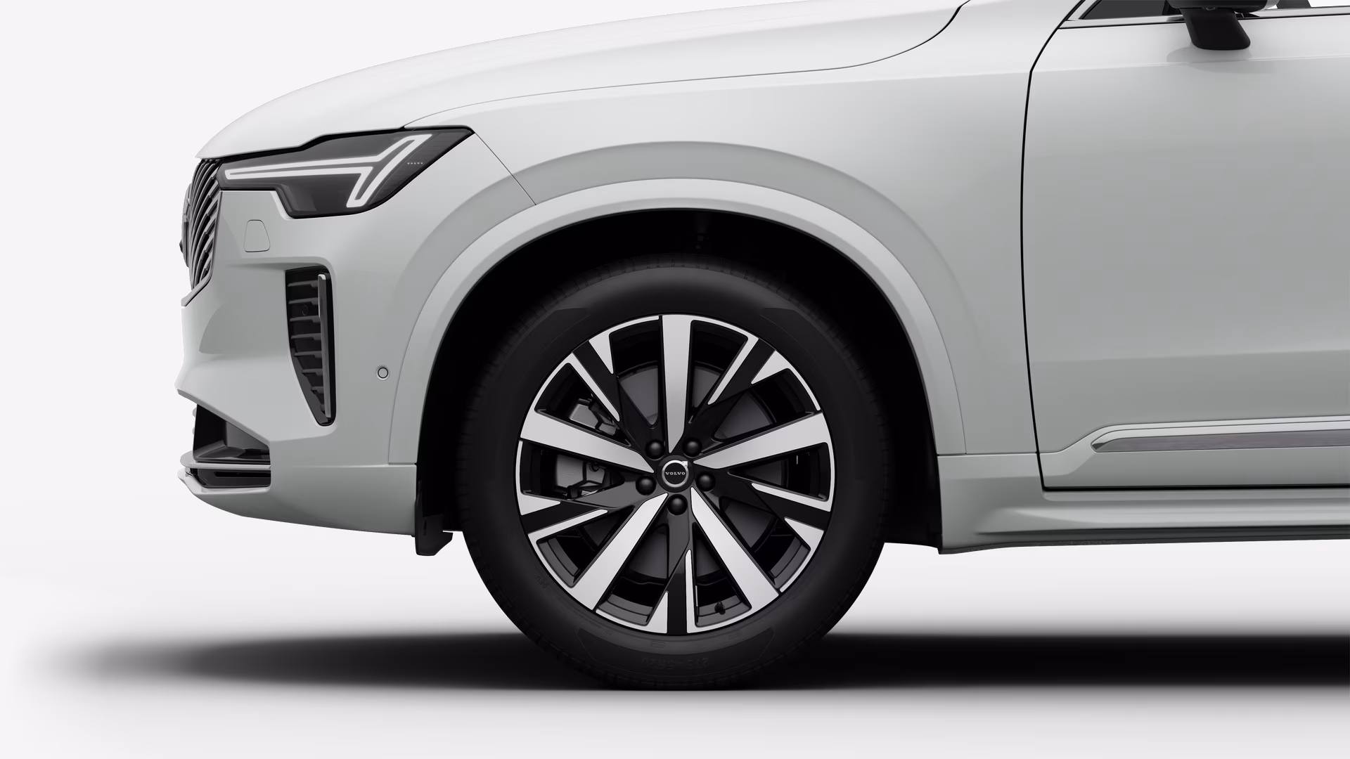 Вид сбоку на переднее колесо и крыло автомобиля Volvo на однотонном студийном фоне.