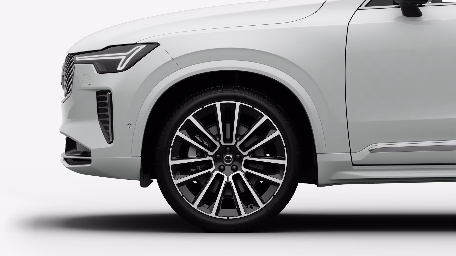 Вид сбоку на переднее колесо и крыло автомобиля Volvo на однотонном студийном фоне.