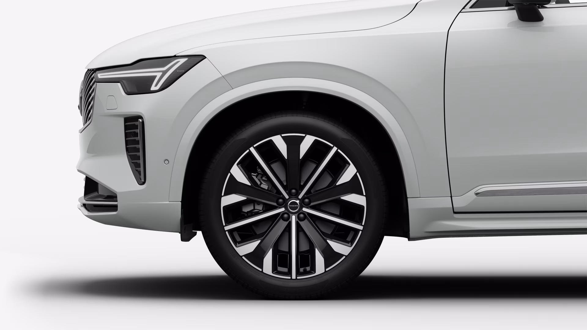 Вид сбоку на переднее колесо и крыло автомобиля Volvo на однотонном студийном фоне.